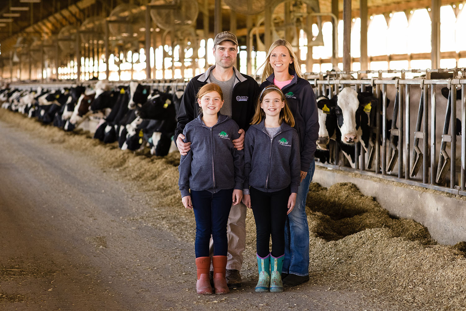 LAMB FARMS 2020_010 Family posing in front of a line of cows