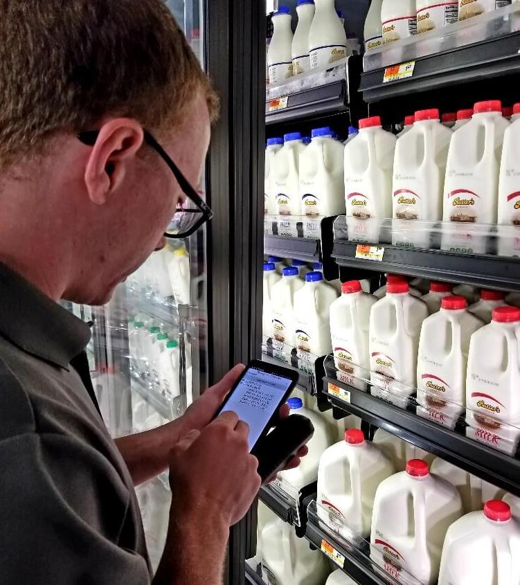 Rep in Store cropped Man on his phone in front of milk in the dairy aisles