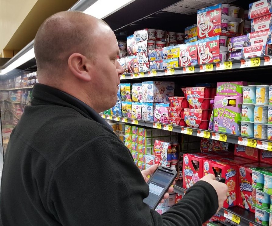 Rep2 in store cropped Man on his phone in front of yogurt in the dairy aisle
