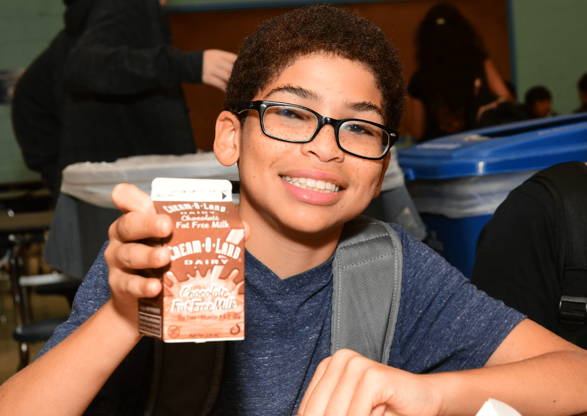 chocolate milk kid Young boy holding a carton of chocolate milk and smiling
