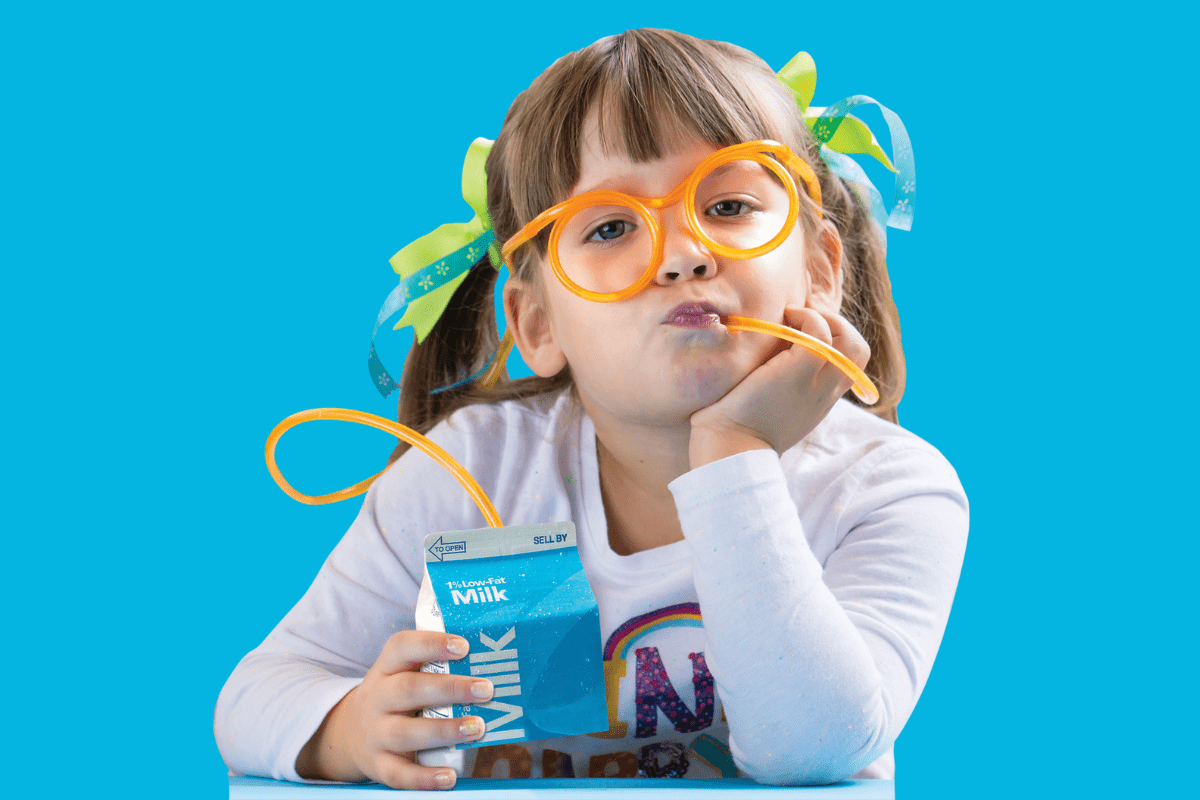 School Nutrition Prgoram – Milk Carton A girl wearing yellow glasses that double as a straw, connected to a bottle of milk.